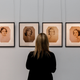 A Sotheby’s staffer in front of portraits of the Mitford sisters from the collection of Deborah Cavendish, Duchess of Devonshire. Photo via Getty.